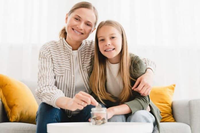 Mom daughter planning earnings savings, putting coins in bank, accounting, money for future, college